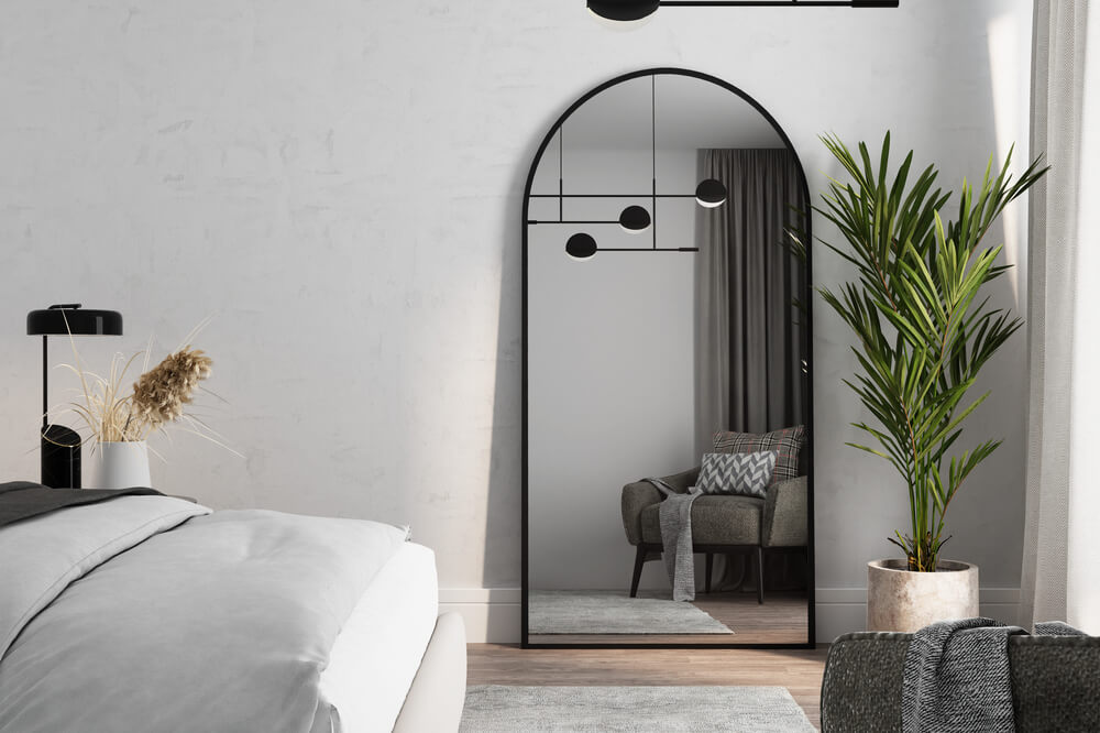 minimalistyczna aranżacja sypialni z dużym lustrem w metalowej ramie - aranżacja 1